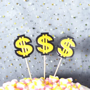 Gold dollar sign cake toppers detail shot, perfect for birthday party dessert table decoration.