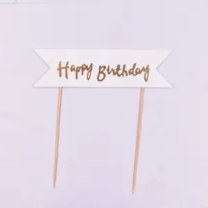 Detailaufnahme des goldenen Happy Birthday Torten-Toppers mit eleganter Schrift auf Flagge.