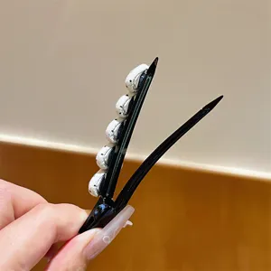 Gedetailleerde close-up van een stijlvolle zwarte eendensnavel haarclip met stoffen decoratie.
