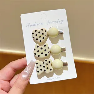 Closeup of cute Korean style polka dot hair clips featuring heart and cat shapes with pearls.