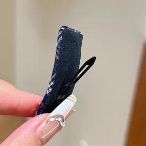 Detailansicht der karierten Haarspange im College-Stil mit Stoffbezug und Antirutschpad.