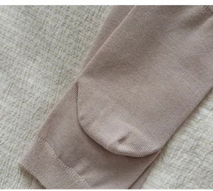 Close-up detail of soft cotton stirrup leg warmers featuring fine knit texture and neat edge.
