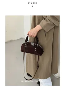 Detailansicht einer Retro-Wildleder-Nietenhandtasche mit Metallbeschlägen und Griffen.