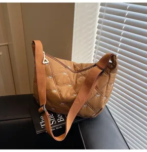 Brown quilted dumpling crossbody bag with cute white bow embroidery and wide strap detail.