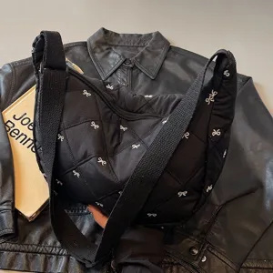 Stylish black quilted dumpling shoulder bag featuring delicate silver bow embroidery.
