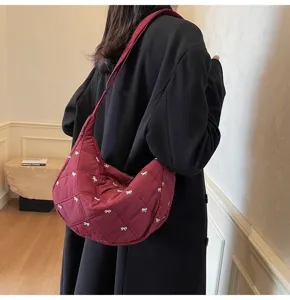 Casual quilted shoulder bag with cute white bow pattern, shown in daily commuting scene.