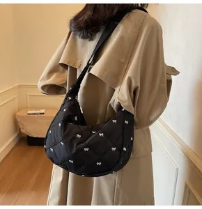 Black quilted shoulder bag featuring cute white bow embroidery, casual dumpling design detail.