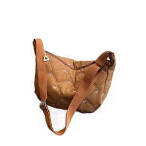 Stylish brown quilted crossbody dumpling bag with cute white bow embroidery for women.