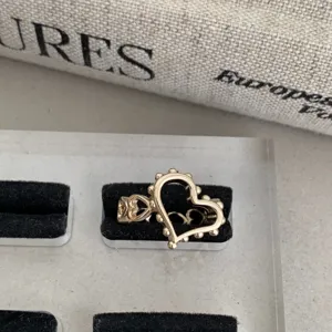 Vue rapprochée d'une bague cœur creux dorée avec bord perl, bijoux rétro français chic.