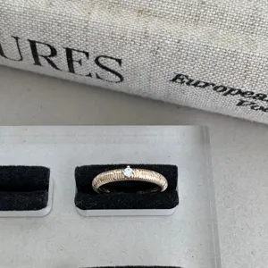 Détail de bague en or texturée délicate avec diamant central scintillant style rétro français.