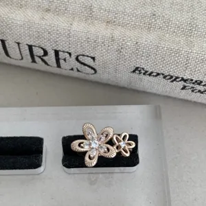 Vue rapprochée de la bague creuse à double fleur scintillante avec pierres et pétales texturés.