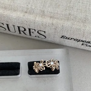 Vue rapprochée d'une bague dentelle florale en or rose avec des pierres étincelantes.