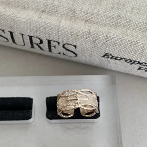 Gros plan d'une bague dorée vintage creuse en croix avec texture gravée et style gothique élégant.