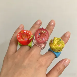 Vue détaillée de bagues en résine fruitées style Y2K avec des strass colorés mignons.