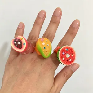 Gros plan détaillé de la bague fruit en résine Y2K avec strass scintillants et couleurs.