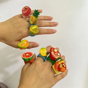 Gros plan détaillé de bagues larges en résine fruitée colorée avec des motifs de fraise.
