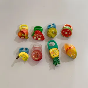 Gros plan sur un ensemble de bagues en résine de fruits tropicaux colorés avec des motifs mignons.