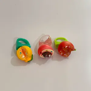 Vue rapprochée détaillée de bagues larges de fruits en résine strass style Y2K.