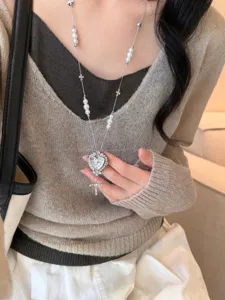 Exquisite detail of long pearl necklace with heart watch pendant and cross charms.