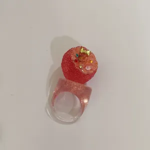 Gros plan détaillé de la bague en résine rose Y2K, avec un design de fruit et des cristaux brillants.