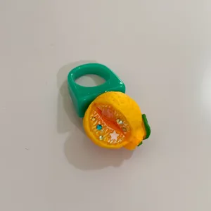 Gros plan de la bague chunky en résine verte Y2K avec un détail de pendentif d'agrumes.