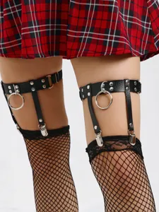 Close-up detail of punk style leather leg garter with metal O-rings worn over fishnet stockings.
