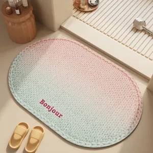 Oval bathroom mat with gradient knit pattern and Bonjour print, absorbent non-slip floor rug.
