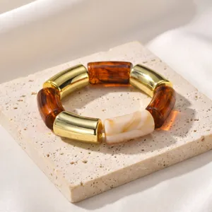 Primer plano detallado del elegante pulsera de resina marron y metal dorado de moda.