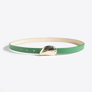 Vista detallada del cinturon verde de mujer con hebilla de concha dorada elegante.