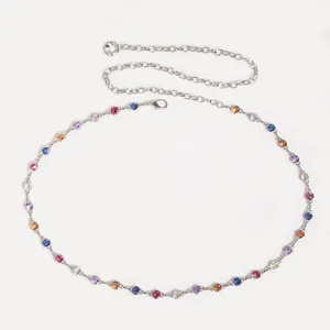 Detail de chaine de taille en metal argente avec des strass colores pour robe de femme.