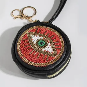 Black round beaded coin purse with evil eye design, gold hardware and wrist strap detail.