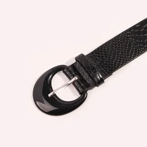 Close-up view of black women's wide belt with crocodile pattern and round buckle.