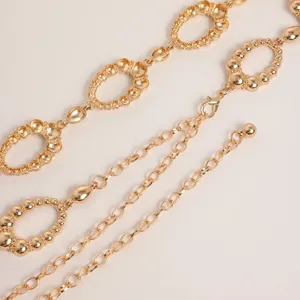 Close-up of vintage gold metal waist chain with carved oval links and delicate dangling chains.