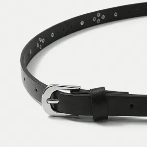 Detail shot of women's black faux leather thin belt with silver buckle and metal eyelet details.