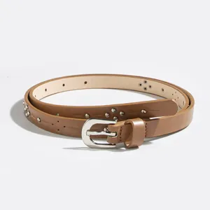 Close-up detail of women brown faux leather belt featuring stylish metal studs and buckle.
