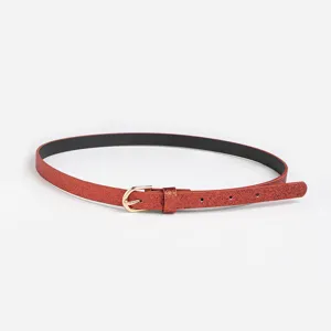 Gros plan d'une fine ceinture rouge pailletée pour enfants avec boucle dorée, accessoire mode.