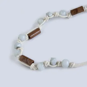 Close-up detail of bohemian braided cord belt featuring wooden beads and resin stone accents.