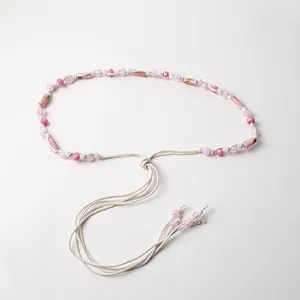 Detail shot of boho pink beaded woven waist cord, elegant casual decorative accessory.