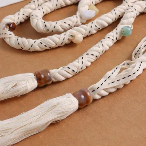 Close-up of bohemian braided cotton waist belt with colorful beads and soft tassel details.