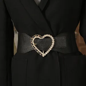 Vista detallada de un elegante cinturón elástico negro con hebilla de corazón de brillantes.