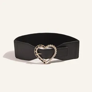 Detalle de cinturón de cintura elástico ancho para mujer con hebilla de metal de corazón de estrás.