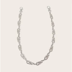 Detailed shot of a stylish silver metal flame chain, edgy hip-hop pants and waist accessory.