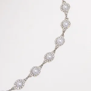 Détail de chaîne fleur perle strass argentée, gros plan accessoire lien métal élégant.
