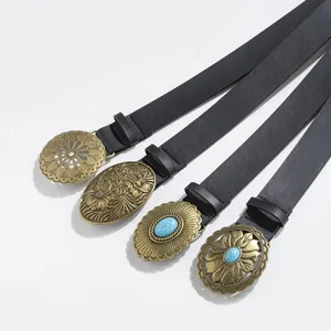 Western vintage black leather belt detail with engraved antique brass and turquoise buckles.
