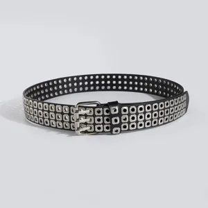 Detailed view of black leather punk double-prong grommet belt with triple rows of square eyelets.