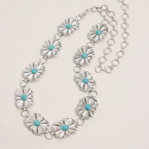 Détail en gros plan d'une chaîne de taille bohème en métal argenté avec fleurs et turquoise.