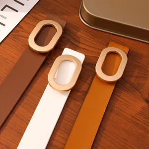 Detail view of women's minimalist leather belts featuring elegant metallic oval buckles.