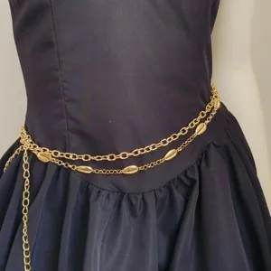 Close-up detail of the multi-layer metal waist chain featuring delicate shell charms and gold links.