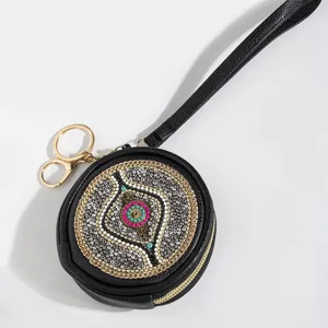 Black round coin purse with wrist strap and intricate bohemian seed bead embellishment.