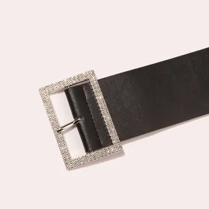 Close-up detail of a women's black leather belt featuring a sparkling rhinestone buckle.